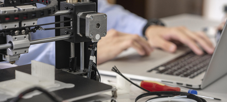 Student setting up 3D printer,using laptop, close up